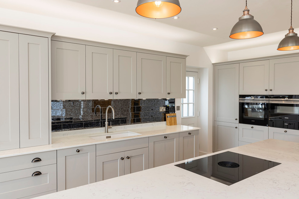 Inspiration for a mid-sized modern kitchen remodel in Hertfordshire with gray backsplash, glass tile backsplash, paneled appliances and an island