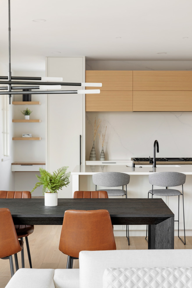 Immagine di un cucina con isola centrale design con ante bianche, top in quarzite, elettrodomestici in acciaio inossidabile, parquet chiaro, pavimento marrone e top bianco