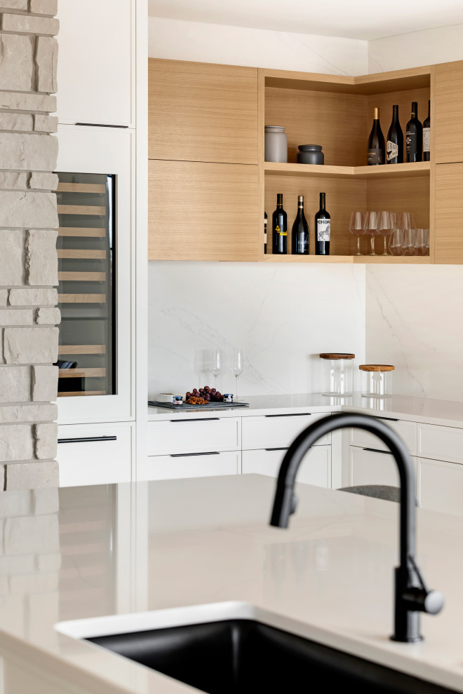 Foto di un cucina con isola centrale contemporaneo con ante bianche, top in quarzite, elettrodomestici in acciaio inossidabile, parquet chiaro, pavimento marrone e top bianco