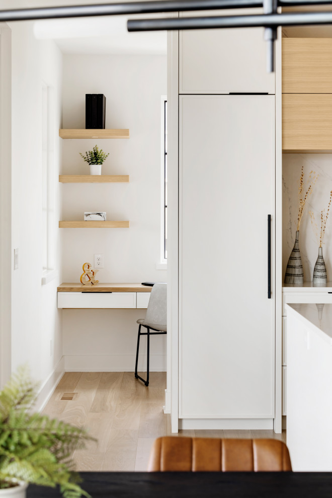 Cette image montre une cuisine design avec des portes de placard blanches, un plan de travail en quartz, un électroménager en acier inoxydable, parquet clair, îlot, un sol marron et un plan de travail blanc.