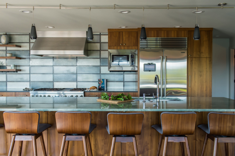 Bild på ett mellanstort 50 tals grön linjärt grönt kök med öppen planlösning, med en undermonterad diskho, släta luckor, skåp i mellenmörkt trä, bänkskiva i kvarts, flerfärgad stänkskydd, rostfria vitvaror, mellanmörkt trägolv, en köksö och brunt golv