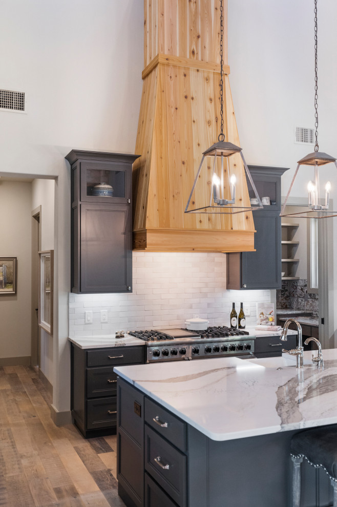Bild på ett stort lantligt flerfärgad flerfärgat kök, med en rustik diskho, skåp i shakerstil, grå skåp, granitbänkskiva, stänkskydd med metallisk yta, stänkskydd i porslinskakel, integrerade vitvaror, ljust trägolv, en köksö och grått golv