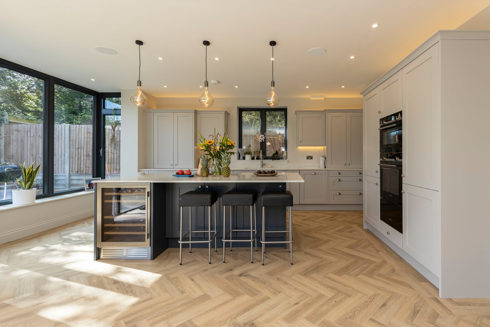 Photo of a large contemporary l-shaped open plan kitchen in Hertfordshire with quartz worktops, an island and white worktops.