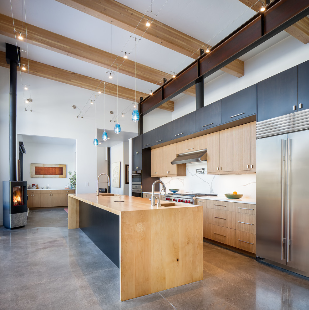 Inspiration for a large modern single-wall concrete floor and gray floor eat-in kitchen remodel in Denver with an undermount sink, flat-panel cabinets, medium tone wood cabinets, wood countertops, white backsplash, stone slab backsplash, stainless steel appliances, an island and multicolored countertops