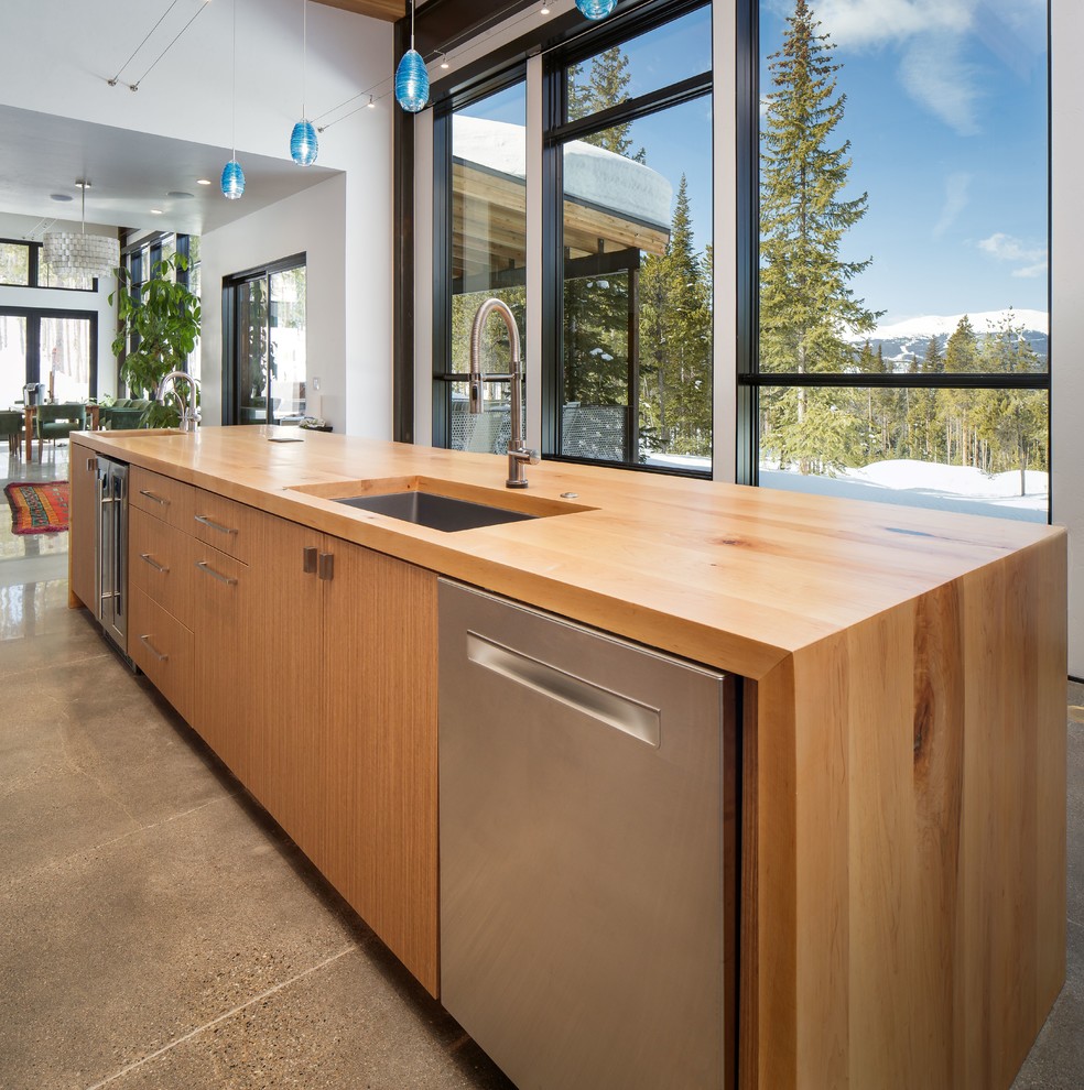 Inspiration for a large modern single-wall concrete floor and gray floor eat-in kitchen remodel in Denver with an undermount sink, flat-panel cabinets, medium tone wood cabinets, white backsplash, stone slab backsplash, stainless steel appliances, an island, multicolored countertops and wood countertops