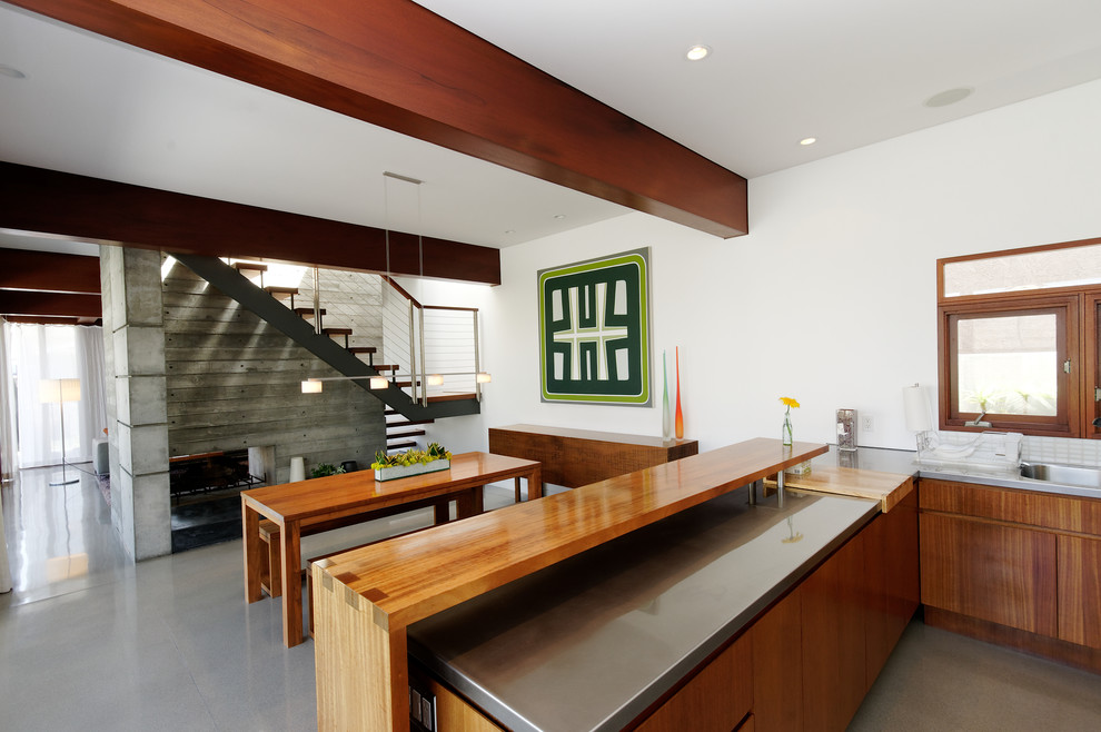 Idées déco pour une cuisine ouverte moderne en bois foncé avec un plan de travail en inox et un placard à porte plane.