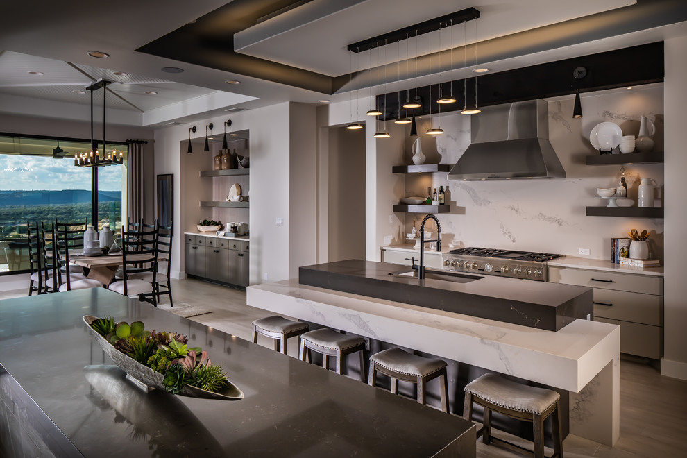 This is an example of an expansive contemporary galley kitchen/diner in Austin with a submerged sink, flat-panel cabinets, quartz worktops, white splashback, stainless steel appliances, porcelain flooring, multiple islands, white worktops, beige cabinets and beige floors.