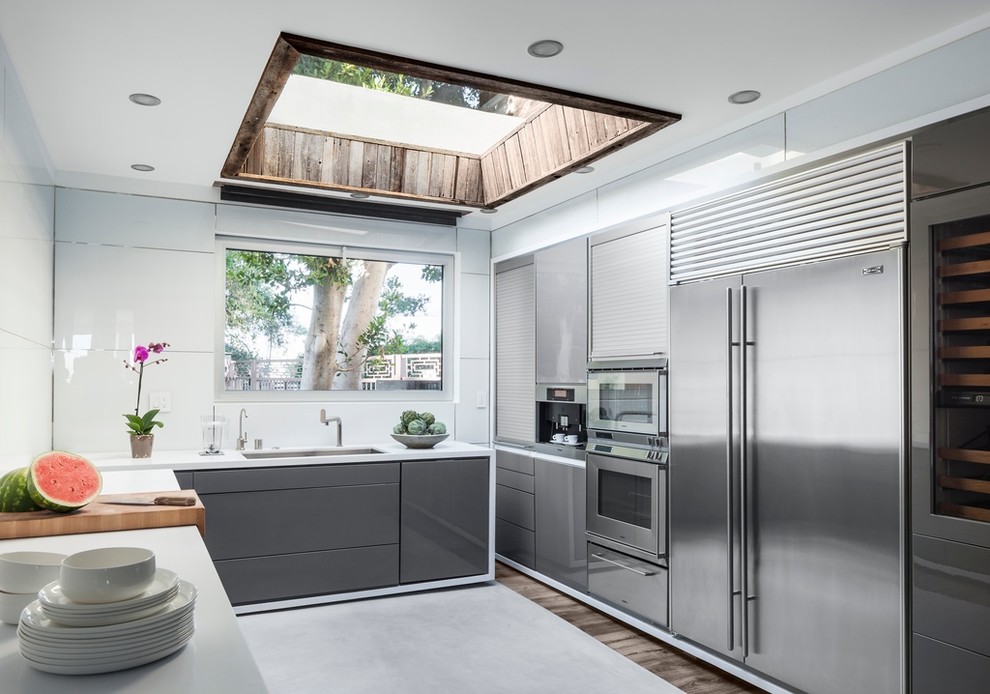 ロサンゼルスにあるコンテンポラリースタイルのおしゃれなキッチン (フラットパネル扉のキャビネット、グレーのキャビネット、シルバーの調理設備、濃色無垢フローリング) の写真