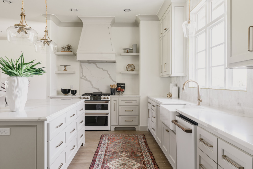 Example of a transitional l-shaped brown floor kitchen design in Oklahoma City with a farmhouse sink, recessed-panel cabinets, white cabinets, white backsplash, white appliances, an island and white countertops