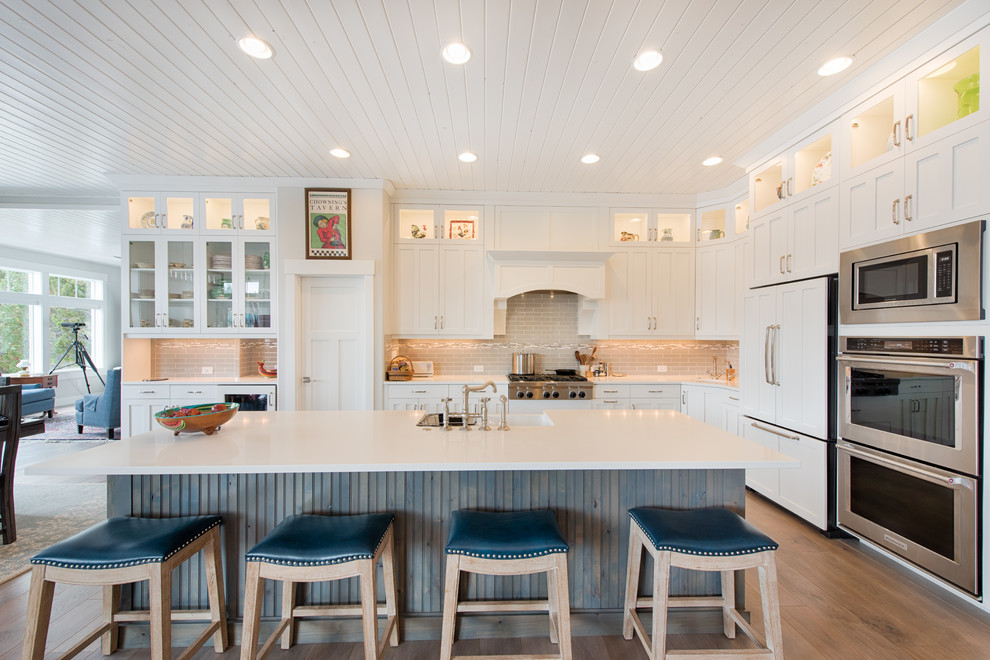 Inspiration for a large transitional l-shaped medium tone wood floor and brown floor eat-in kitchen remodel in Boise with a double-bowl sink, shaker cabinets, white cabinets, quartzite countertops, gray backsplash, glass tile backsplash, white appliances and an island