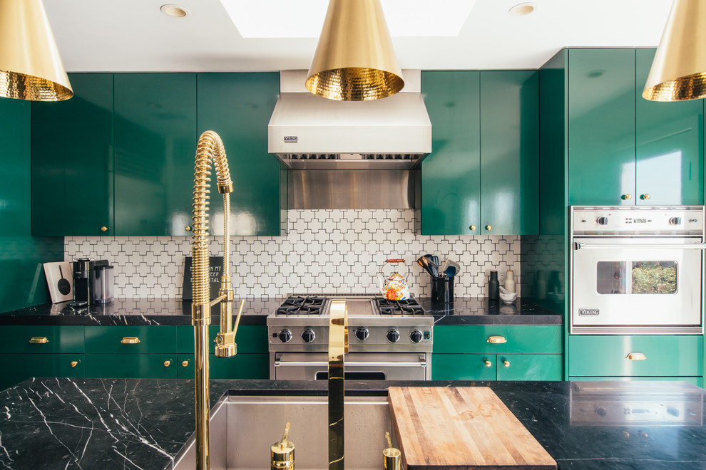 Example of a trendy galley kitchen design in Los Angeles with an undermount sink, flat-panel cabinets, green cabinets, white backsplash, stainless steel appliances, an island and black countertops