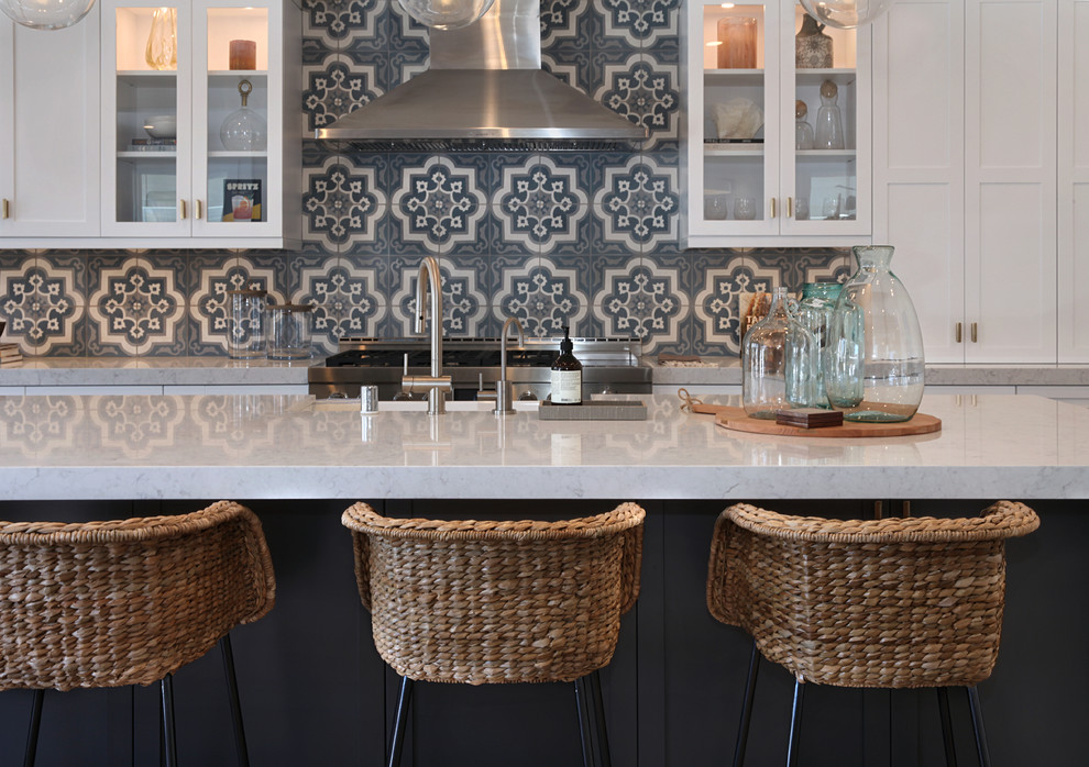 Inspiration for a mid-sized coastal single-wall medium tone wood floor and brown floor open concept kitchen remodel in Orange County with a farmhouse sink, shaker cabinets, white cabinets, marble countertops, multicolored backsplash, cement tile backsplash, paneled appliances, an island and white countertops