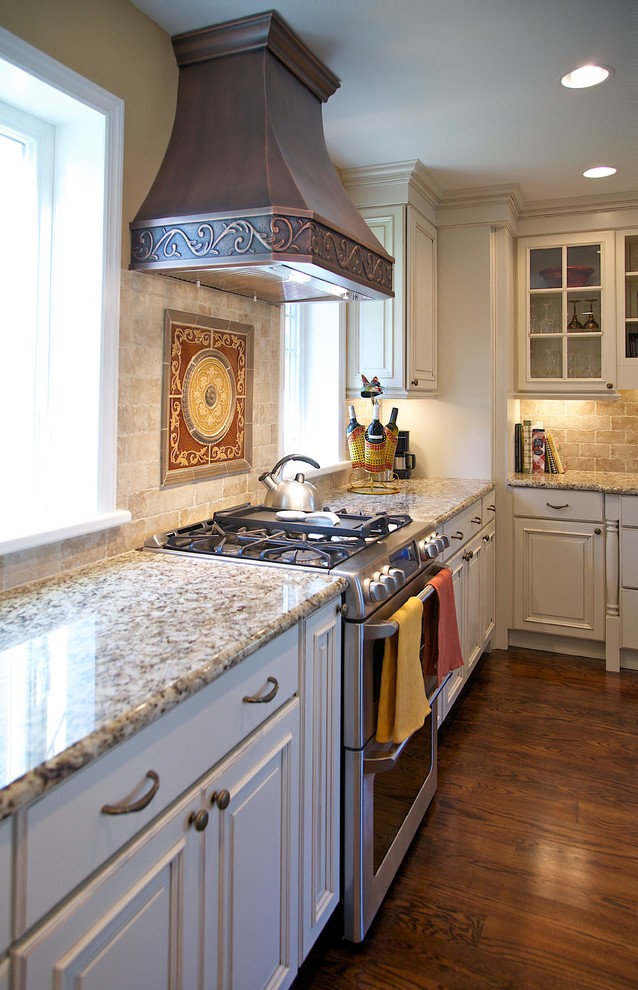 Medelhavsstil inredning av ett mellanstort kök, med en undermonterad diskho, luckor med upphöjd panel, vita skåp, granitbänkskiva, beige stänkskydd, stänkskydd i keramik, rostfria vitvaror, mellanmörkt trägolv, en halv köksö och brunt golv