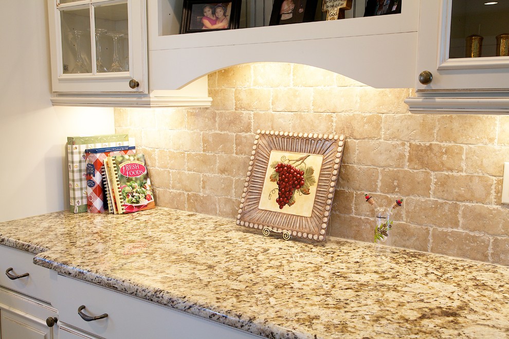 Bild på ett mellanstort medelhavsstil kök, med en undermonterad diskho, luckor med upphöjd panel, vita skåp, granitbänkskiva, beige stänkskydd, stänkskydd i keramik, rostfria vitvaror, mellanmörkt trägolv, en halv köksö och brunt golv