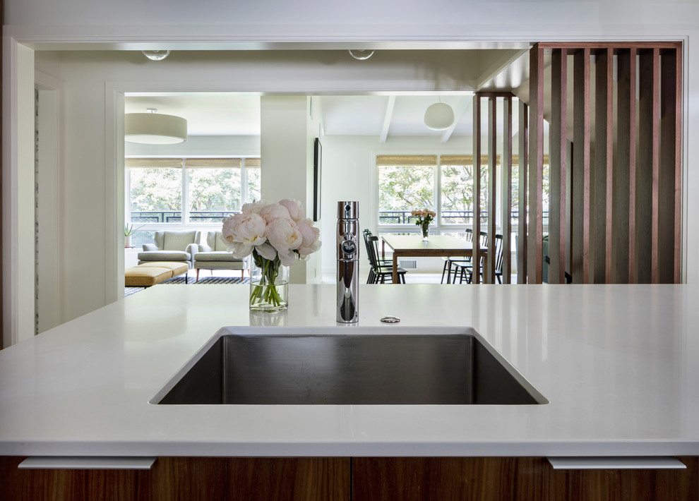 Large modern u-shaped kitchen/diner in Kansas City with a submerged sink, flat-panel cabinets, dark wood cabinets, composite countertops, white splashback, stone slab splashback, stainless steel appliances, concrete flooring and an island.