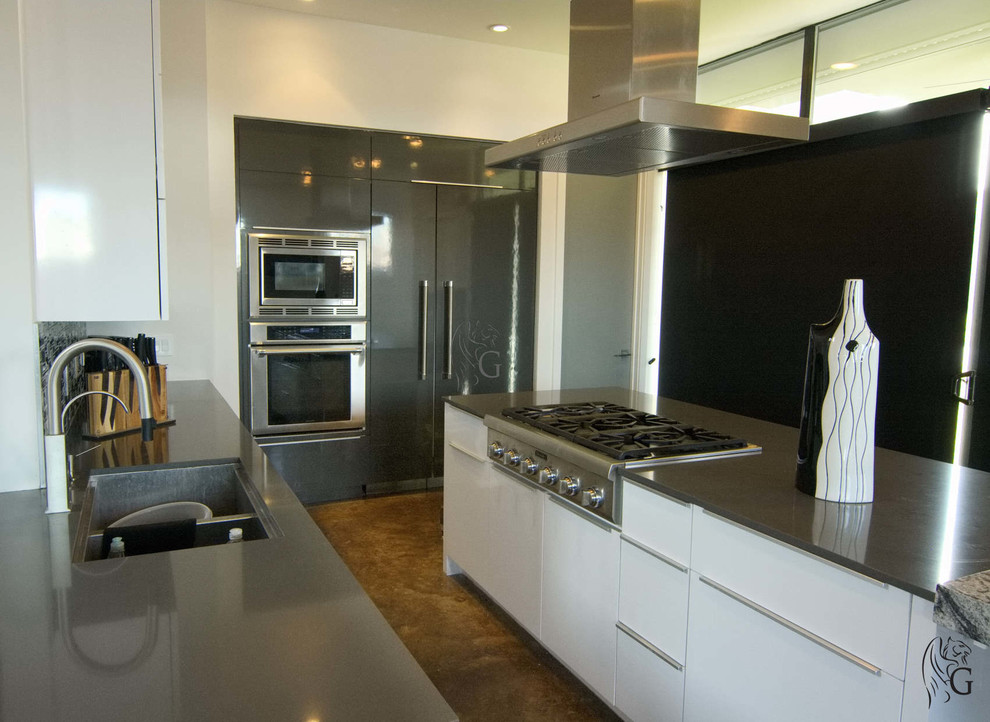Foto på ett stort funkis grå kök, med en dubbel diskho, släta luckor, vita skåp, granitbänkskiva, grått stänkskydd, stänkskydd i mosaik, färgglada vitvaror, betonggolv, en köksö och brunt golv