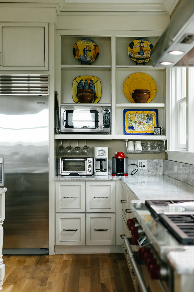 Idéer för vintage grått l-kök, med luckor med infälld panel, beige skåp, rostfria vitvaror, mellanmörkt trägolv, en köksö och brunt golv