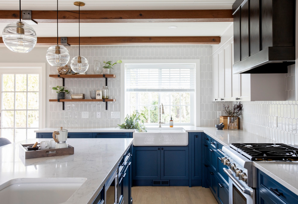 Foto på ett lantligt vit kök, med en undermonterad diskho, skåp i shakerstil, bänkskiva i kvartsit, blått stänkskydd, rostfria vitvaror, mellanmörkt trägolv och en köksö