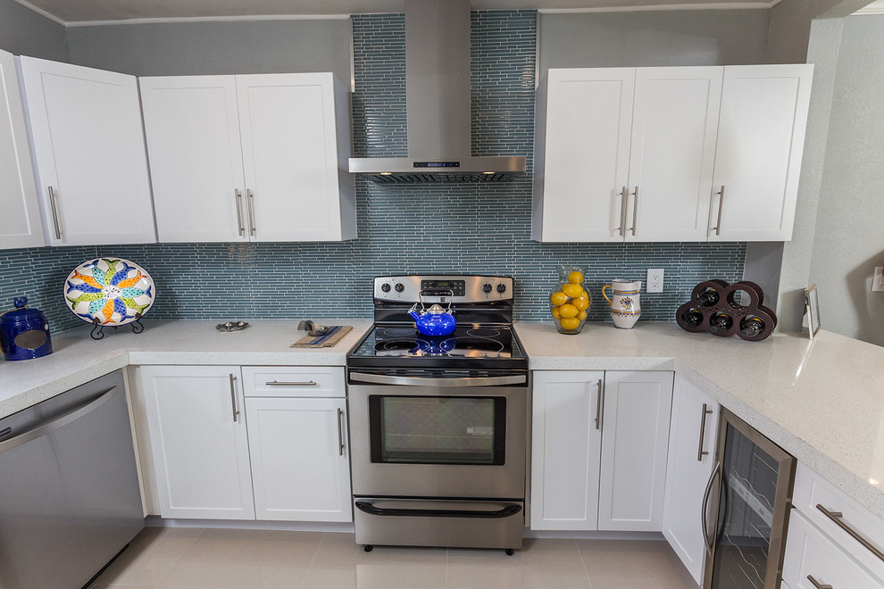 マイアミにあるお手頃価格の中くらいなコンテンポラリースタイルのおしゃれなキッチン (エプロンフロントシンク、シェーカースタイル扉のキャビネット、白いキャビネット、御影石カウンター、青いキッチンパネル、ボーダータイルのキッチンパネル、シルバーの調理設備、リノリウムの床、白い床) の写真
