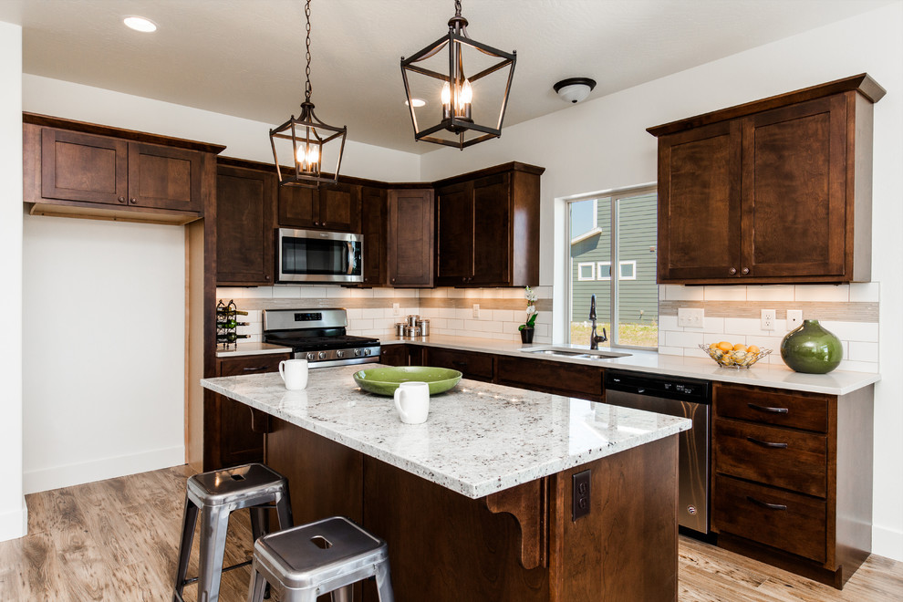 Example of a mid-sized classic l-shaped laminate floor and yellow floor open concept kitchen design in Other with an undermount sink, shaker cabinets, dark wood cabinets, quartz countertops, beige backsplash, subway tile backsplash, stainless steel appliances, an island and beige countertops