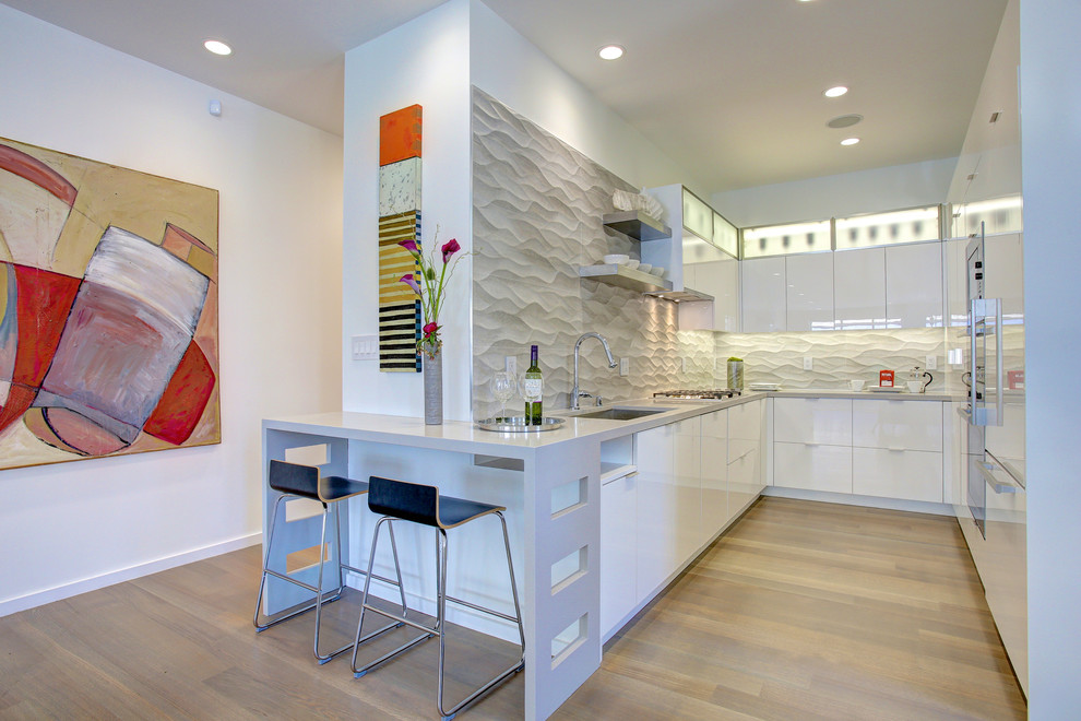 Photo of a contemporary u-shaped enclosed kitchen in San Francisco with a submerged sink, flat-panel cabinets, white cabinets, white splashback and integrated appliances.
