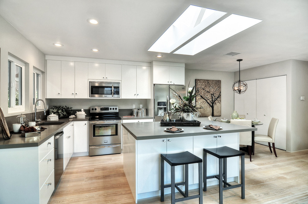 Moderne Küche mit Waschbecken, hellem Holzboden und Kücheninsel in Orange County