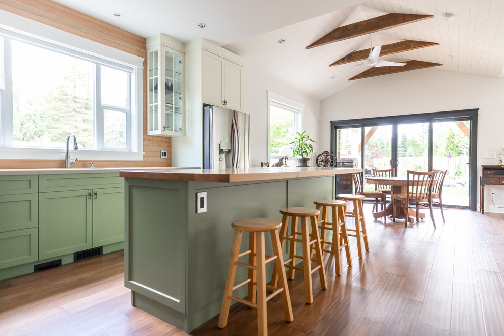 Example of a large arts and crafts u-shaped dark wood floor and brown floor eat-in kitchen design in Vancouver with an undermount sink, recessed-panel cabinets, blue cabinets, wood countertops, brown backsplash, wood backsplash, stainless steel appliances, an island and brown countertops