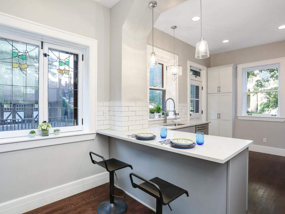 Mid-sized elegant u-shaped dark wood floor and brown floor eat-in kitchen photo in Detroit with an undermount sink, recessed-panel cabinets, white cabinets, quartz countertops, white backsplash, subway tile backsplash, stainless steel appliances, a peninsula and white countertops