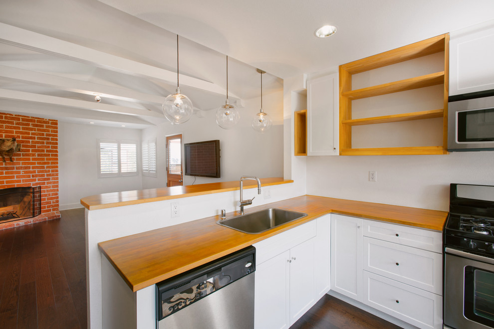 Mid-Century Küche ohne Insel in L-Form mit Waschbecken, offenen Schränken, hellen Holzschränken, Arbeitsplatte aus Holz, Küchengeräten aus Edelstahl und braunem Holzboden in Orange County