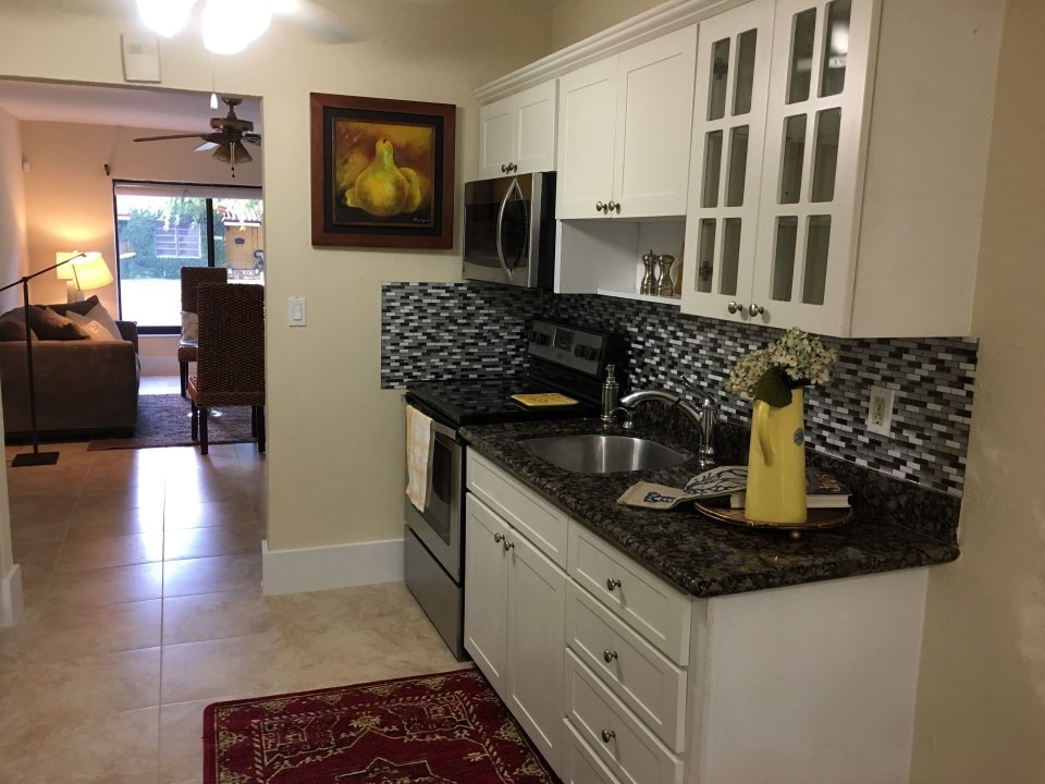 Photo of a medium sized classic single-wall enclosed kitchen in Miami with a submerged sink, shaker cabinets, white cabinets, granite worktops, multi-coloured splashback, matchstick tiled splashback, stainless steel appliances, travertine flooring, no island and beige floors.