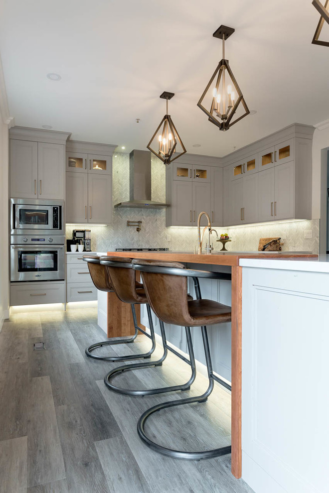Inspiration for a large traditional l-shaped kitchen/diner in Vancouver with a belfast sink, shaker cabinets, grey cabinets, engineered stone countertops, an island, white worktops, grey splashback, marble splashback, dark hardwood flooring and brown floors.