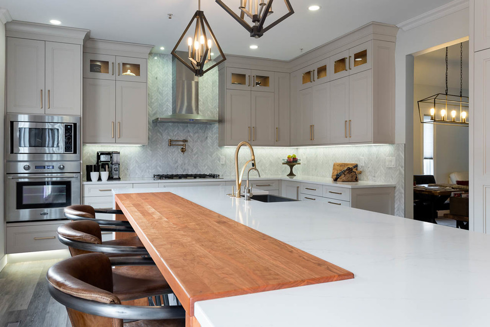 Klassisk inredning av ett stort vit vitt kök, med en rustik diskho, skåp i shakerstil, grå skåp, bänkskiva i kvarts, en köksö, grått stänkskydd, stänkskydd i marmor, mörkt trägolv och brunt golv