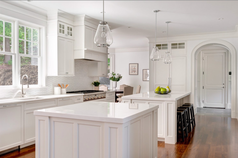 Inspiration for a timeless medium tone wood floor eat-in kitchen remodel in Boston with an undermount sink, shaker cabinets, white cabinets, multicolored backsplash, stainless steel appliances, two islands and white countertops