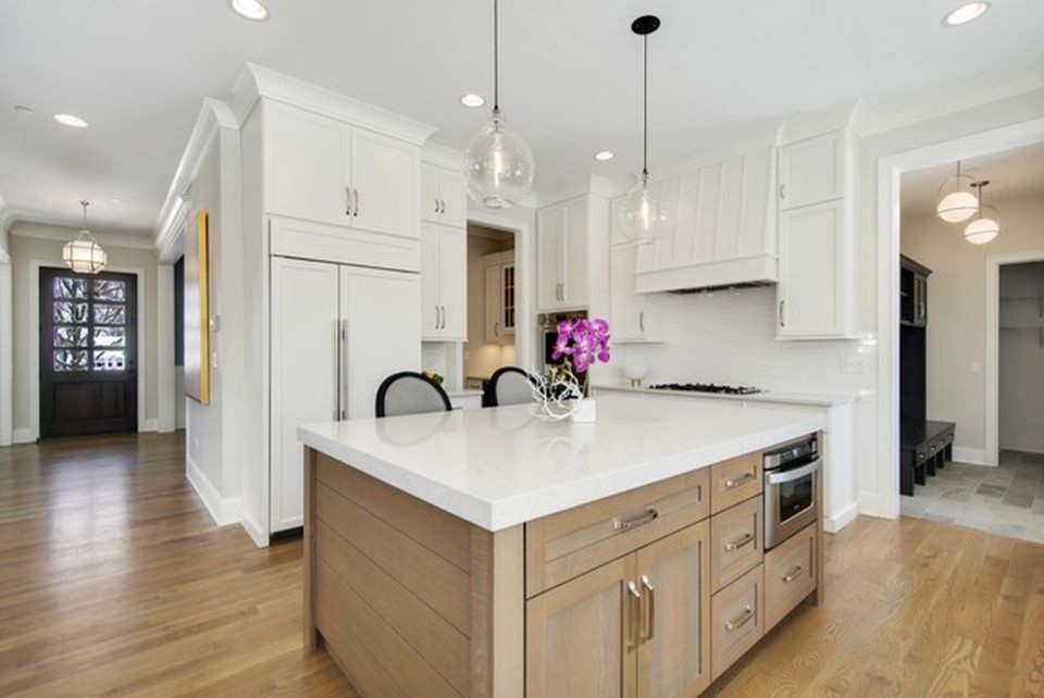 Inspiration for a medium sized contemporary u-shaped kitchen in Chicago with shaker cabinets, white cabinets, engineered stone countertops, white splashback, stainless steel appliances, medium hardwood flooring, an island, brown floors and white worktops.