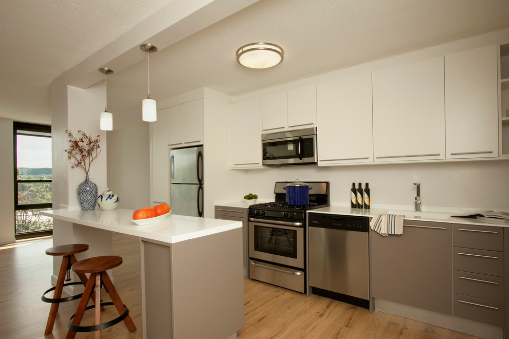 Modern inredning av ett litet linjärt kök med öppen planlösning, med en integrerad diskho, släta luckor, vita skåp, bänkskiva i koppar, rostfria vitvaror, ljust trägolv och en köksö