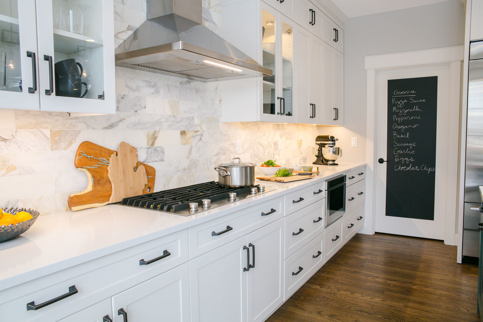 Example of a large transitional single-wall medium tone wood floor and brown floor eat-in kitchen design in Denver with an undermount sink, shaker cabinets, white cabinets, quartz countertops, multicolored backsplash, marble backsplash, stainless steel appliances, an island and white countertops