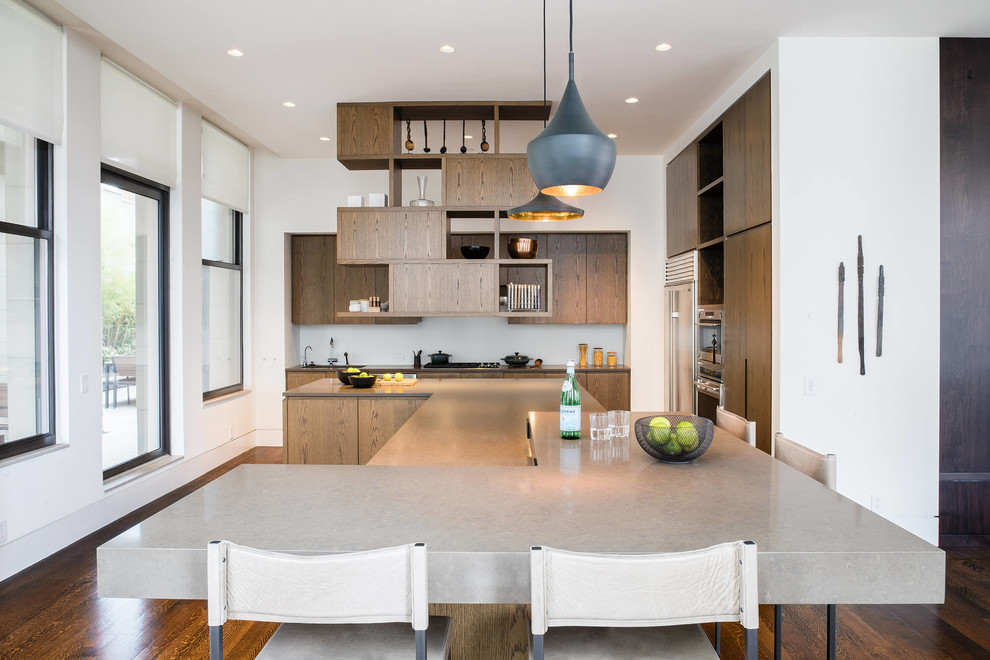 Design ideas for a large contemporary kitchen in New York with a double-bowl sink, flat-panel cabinets, medium wood cabinets, engineered stone countertops, white splashback, glass sheet splashback, stainless steel appliances, medium hardwood flooring, an island, brown floors and beige worktops.