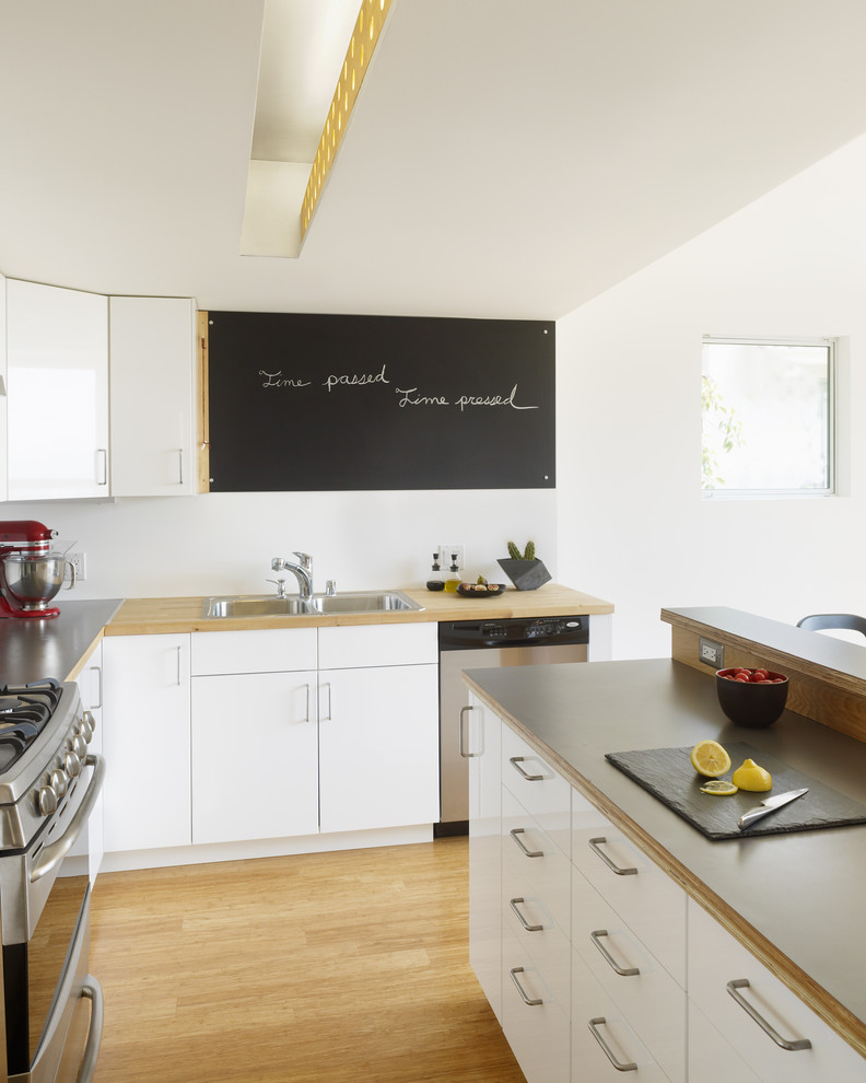 Diseño de cocina contemporánea con fregadero encastrado, encimera de laminado, armarios con paneles lisos, puertas de armario blancas y electrodomésticos de acero inoxidable