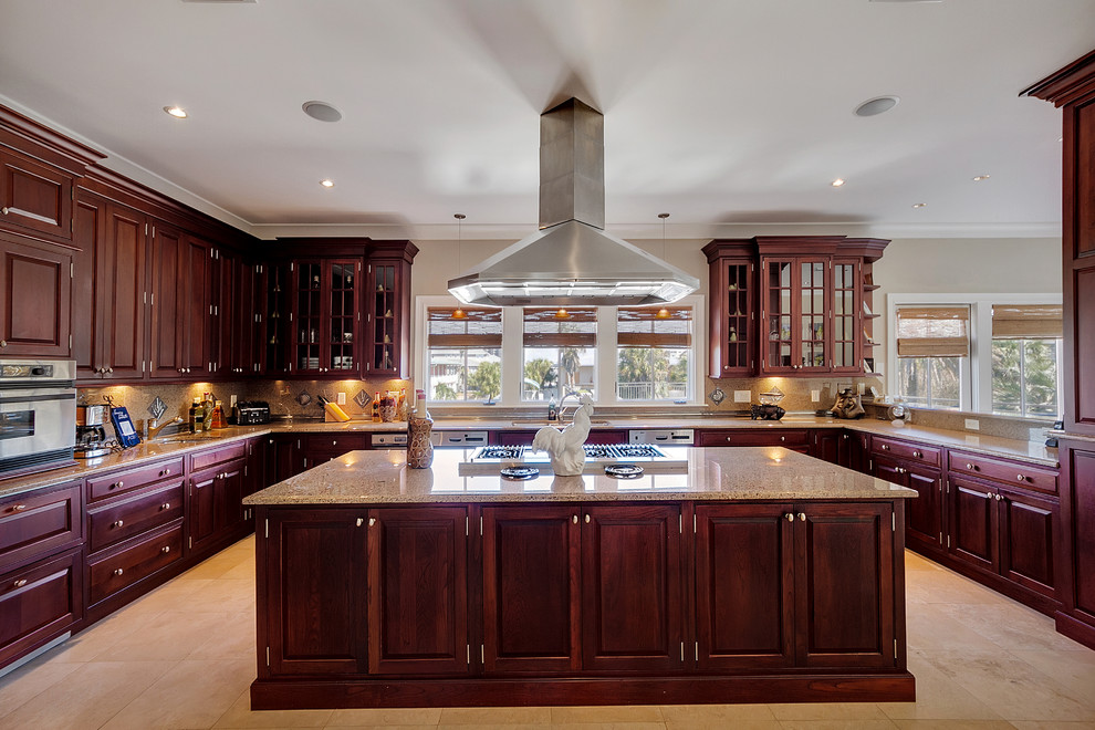 This is an example of a classic u-shaped kitchen in Miami with a submerged sink, raised-panel cabinets, dark wood cabinets, beige splashback, stainless steel appliances and an island.