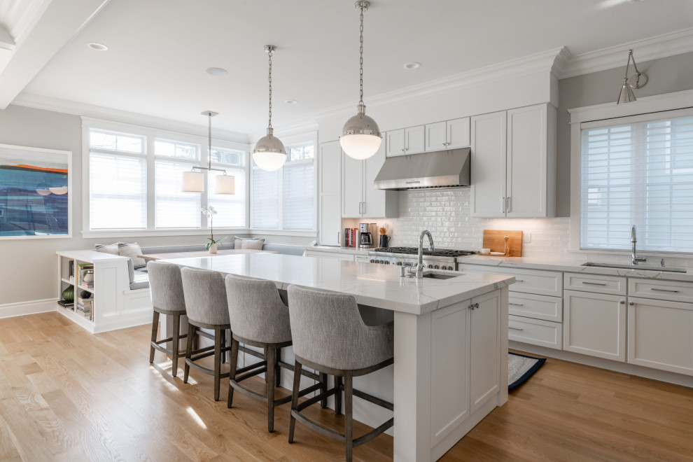 Photo of a large classic l-shaped kitchen in DC Metro with a submerged sink, shaker cabinets, white cabinets, white splashback, ceramic splashback, stainless steel appliances, an island, beige floors and grey worktops.
