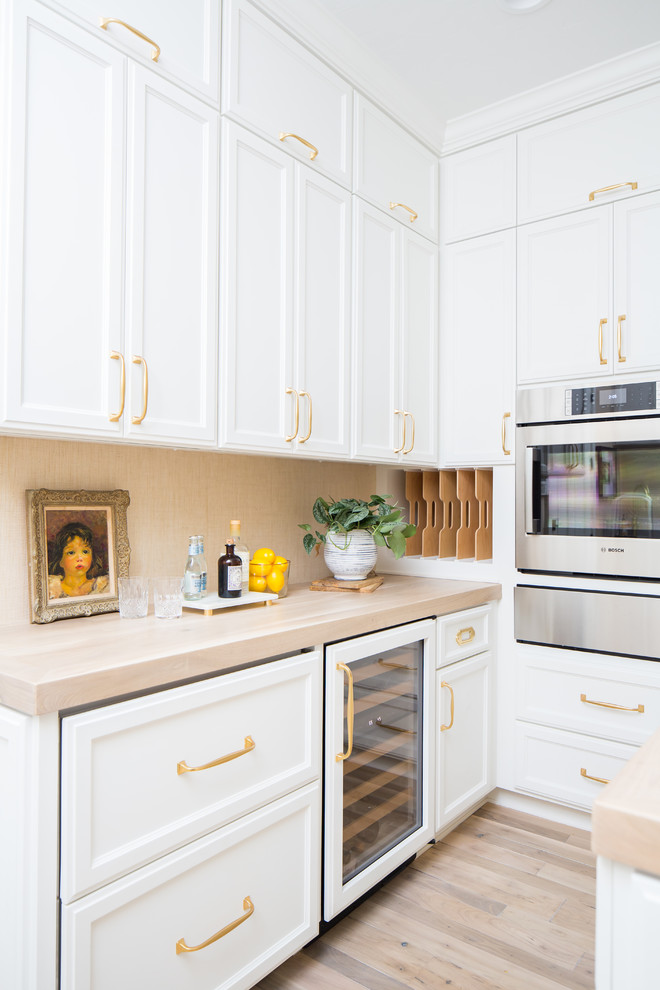 Klassische Küche mit weißen Schränken, Arbeitsplatte aus Holz, Elektrogeräten mit Frontblende, braunem Holzboden und Kücheninsel in San Diego
