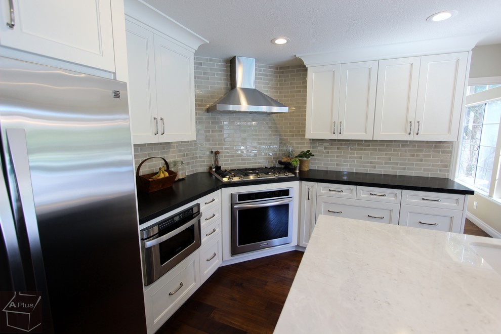 Example of a large trendy l-shaped medium tone wood floor eat-in kitchen design in Orange County with a drop-in sink, shaker cabinets, white cabinets, quartz countertops, beige backsplash, porcelain backsplash, stainless steel appliances and an island