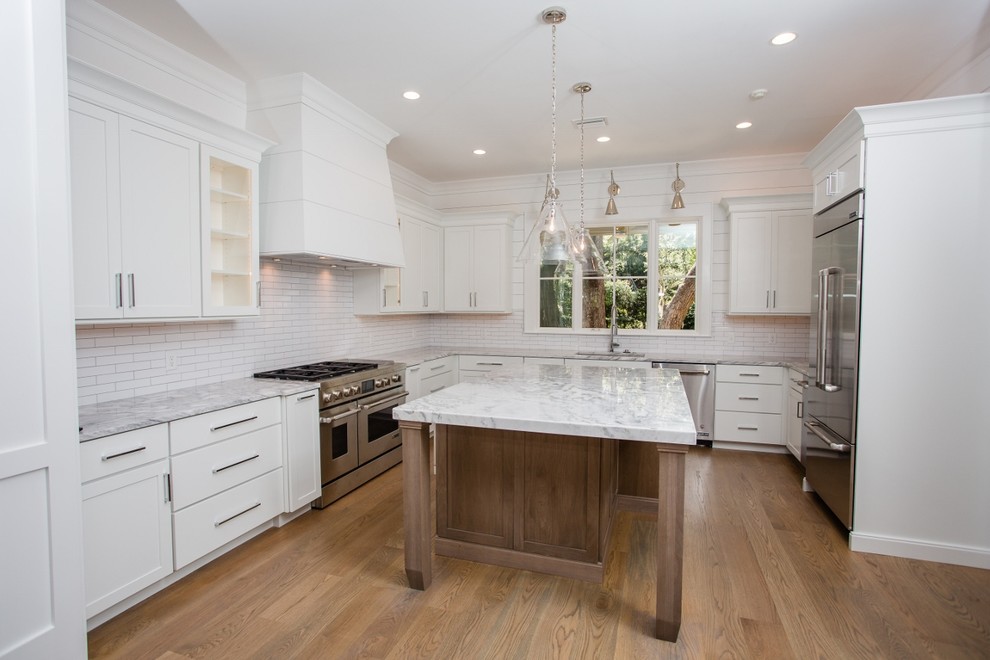 Inspiration for a large contemporary u-shaped medium tone wood floor and brown floor enclosed kitchen remodel in Jacksonville with an undermount sink, shaker cabinets, white cabinets, quartzite countertops, white backsplash, subway tile backsplash, stainless steel appliances and an island