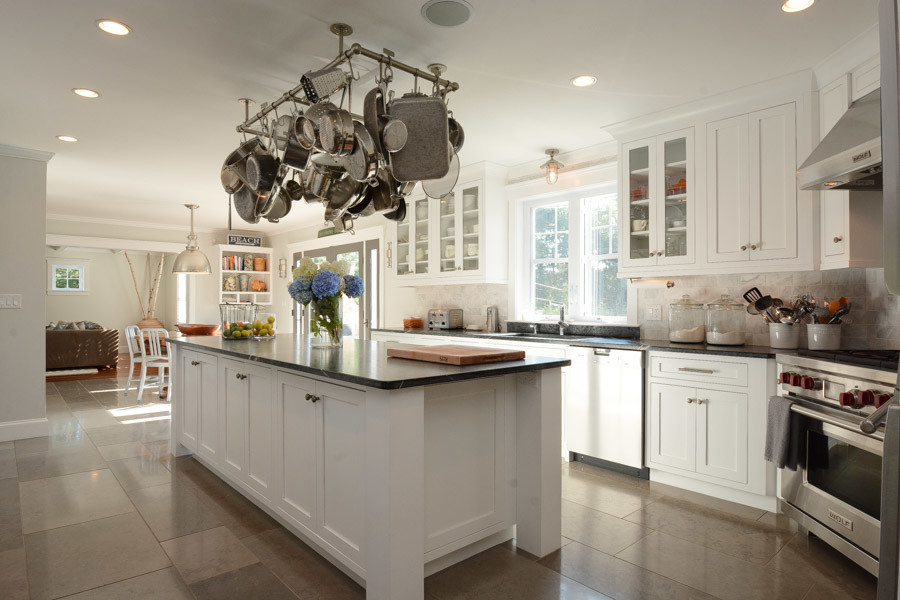 Example of a mid-sized transitional l-shaped concrete floor eat-in kitchen design in Boston with a drop-in sink, recessed-panel cabinets, white cabinets, granite countertops, beige backsplash, stone tile backsplash, stainless steel appliances and an island