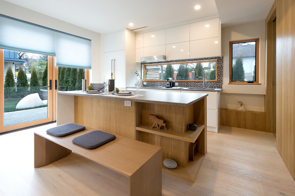 Foto på ett mellanstort funkis grå kök, med en undermonterad diskho, släta luckor, vita skåp, bänkskiva i kvarts, stänkskydd i mosaik, integrerade vitvaror, ljust trägolv, en köksö, gult golv och flerfärgad stänkskydd