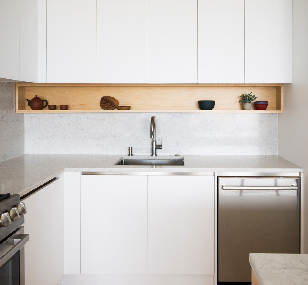 Medium sized modern l-shaped kitchen/diner in Chicago with a submerged sink, flat-panel cabinets, white cabinets, quartz worktops, grey splashback, stainless steel appliances, light hardwood flooring, an island, yellow floors and grey worktops.