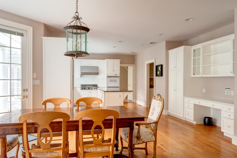 Exempel på ett stort kök, med en nedsänkt diskho, luckor med upphöjd panel, vita skåp, bänkskiva i kvartsit, rostfria vitvaror, mellanmörkt trägolv och en köksö