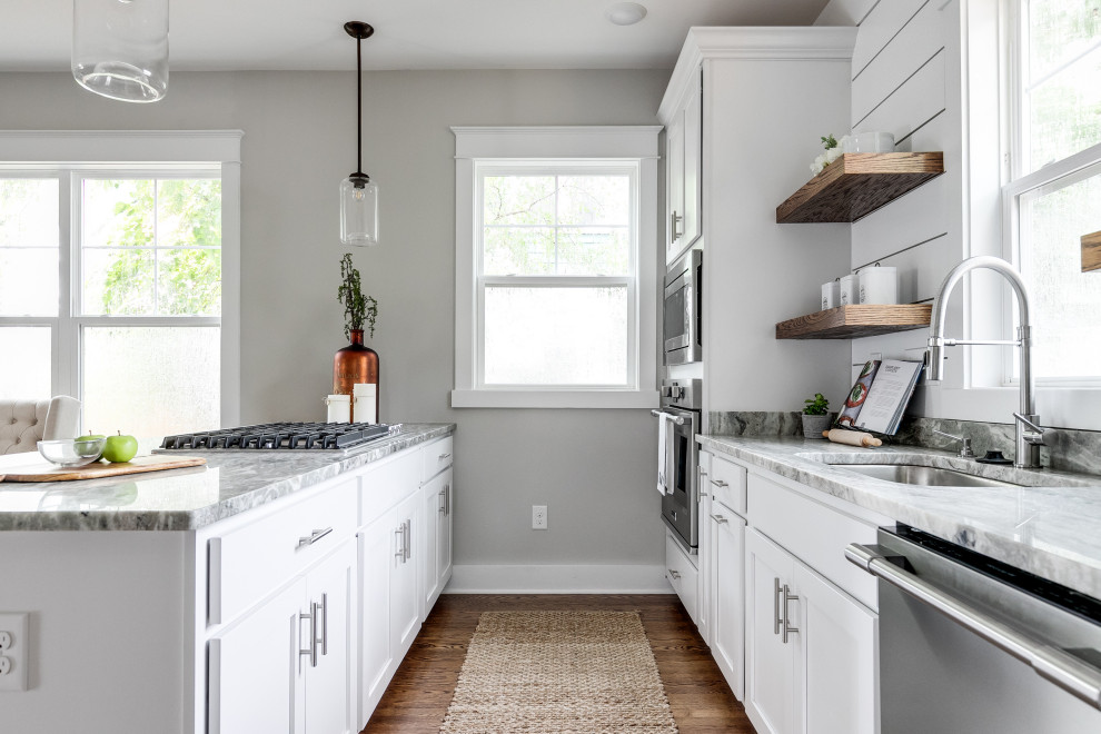 Exempel på ett stort amerikanskt grå grått kök, med en undermonterad diskho, luckor med infälld panel, vita skåp, granitbänkskiva, vitt stänkskydd, rostfria vitvaror, mellanmörkt trägolv, en köksö och brunt golv