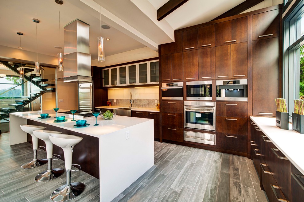 Immagine di una cucina a L design con ante lisce, ante in legno bruno e elettrodomestici in acciaio inossidabile