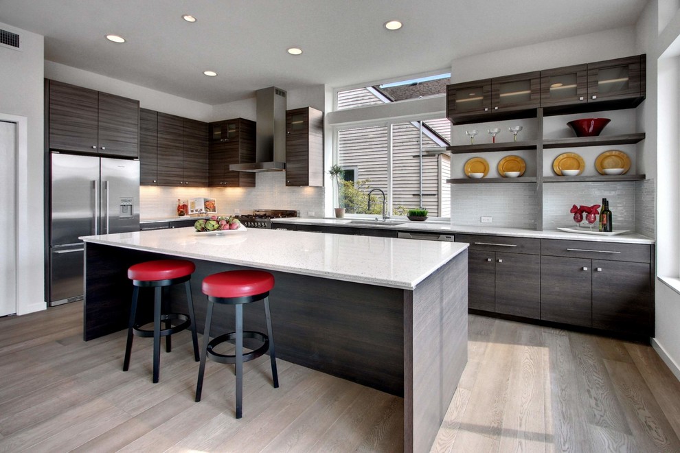 Foto på ett stort funkis kök, med en köksö, släta luckor, grå skåp, bänkskiva i kvarts, vitt stänkskydd, stänkskydd i glaskakel, rostfria vitvaror och ljust trägolv